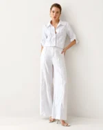 Modelo em pé de corpo inteiro vestindo conjunto de camisa alfaiataria em puro linho off-white e calça pantalona