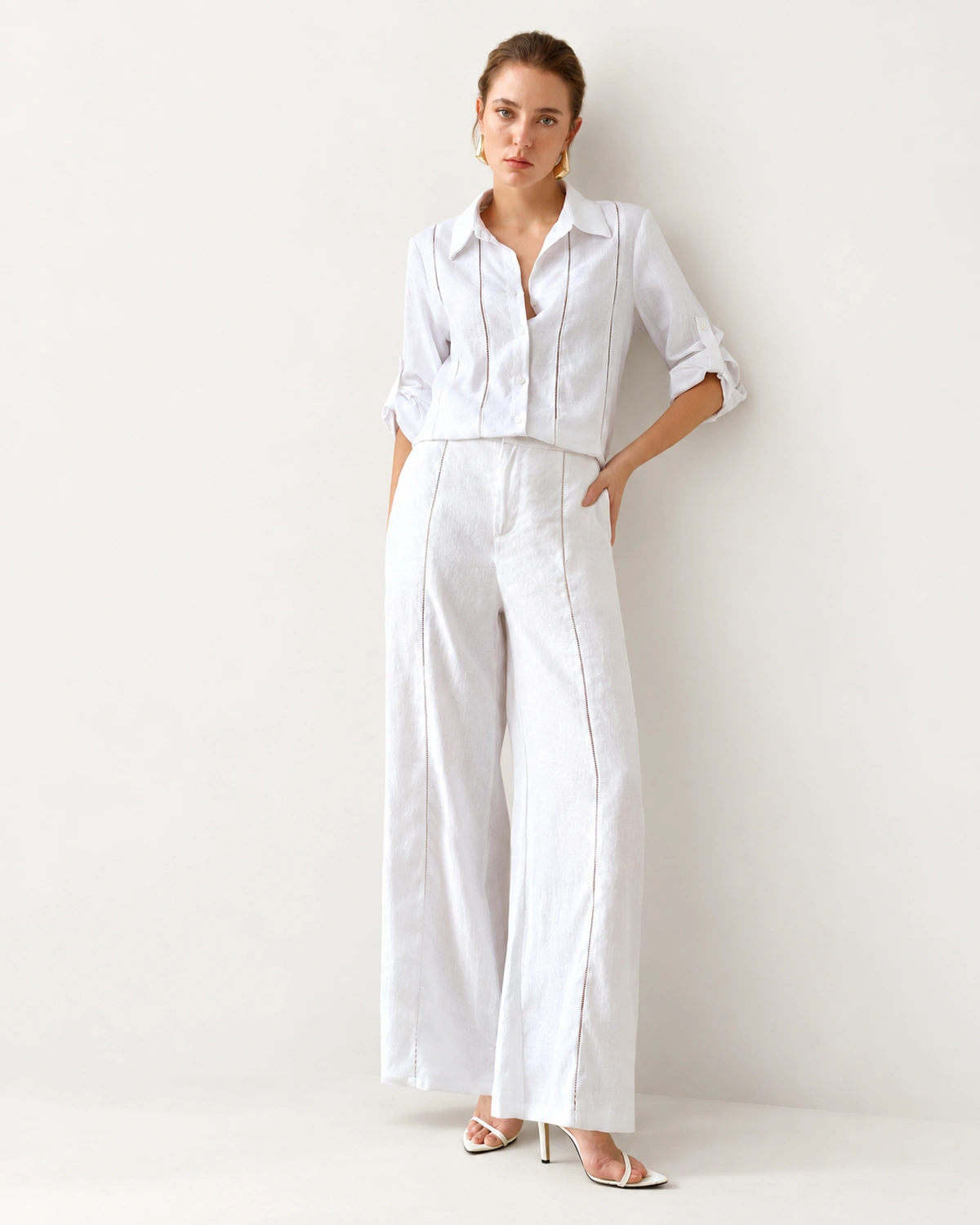 Modelo em pé de corpo inteiro vestindo conjunto de camisa alfaiataria em puro linho off-white e calça pantalona