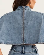 Close posterior da blusa cropped jeans lavagem clara destacando o zíper metálico aparente vestida pela modelo em estúdio mineral