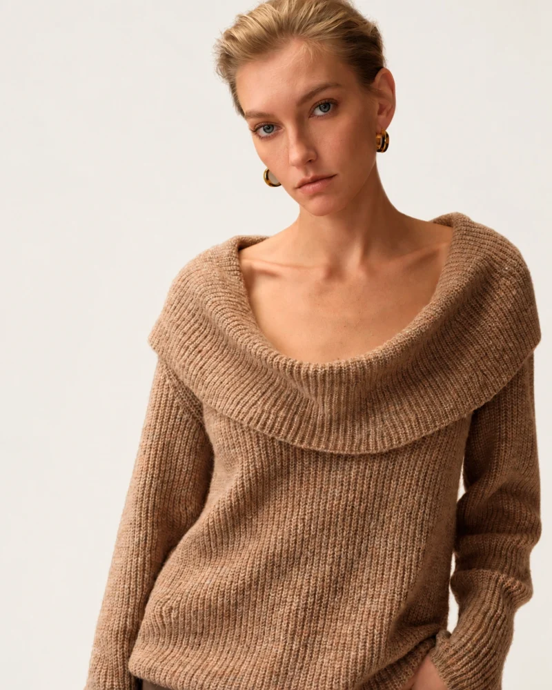 Plano médio da modelo com suéter tricot canelado gola degagê destacando as clavículas e textura canelada.