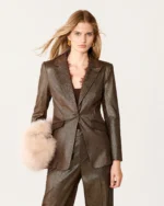 Vista das costas da modelo com blazer alfaiataria bronze estruturado e calça combinando.