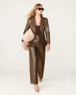 Modelo caminhando com blazer de alfaiataria bronze metalizado estruturado com calça pantalona em estúdio.