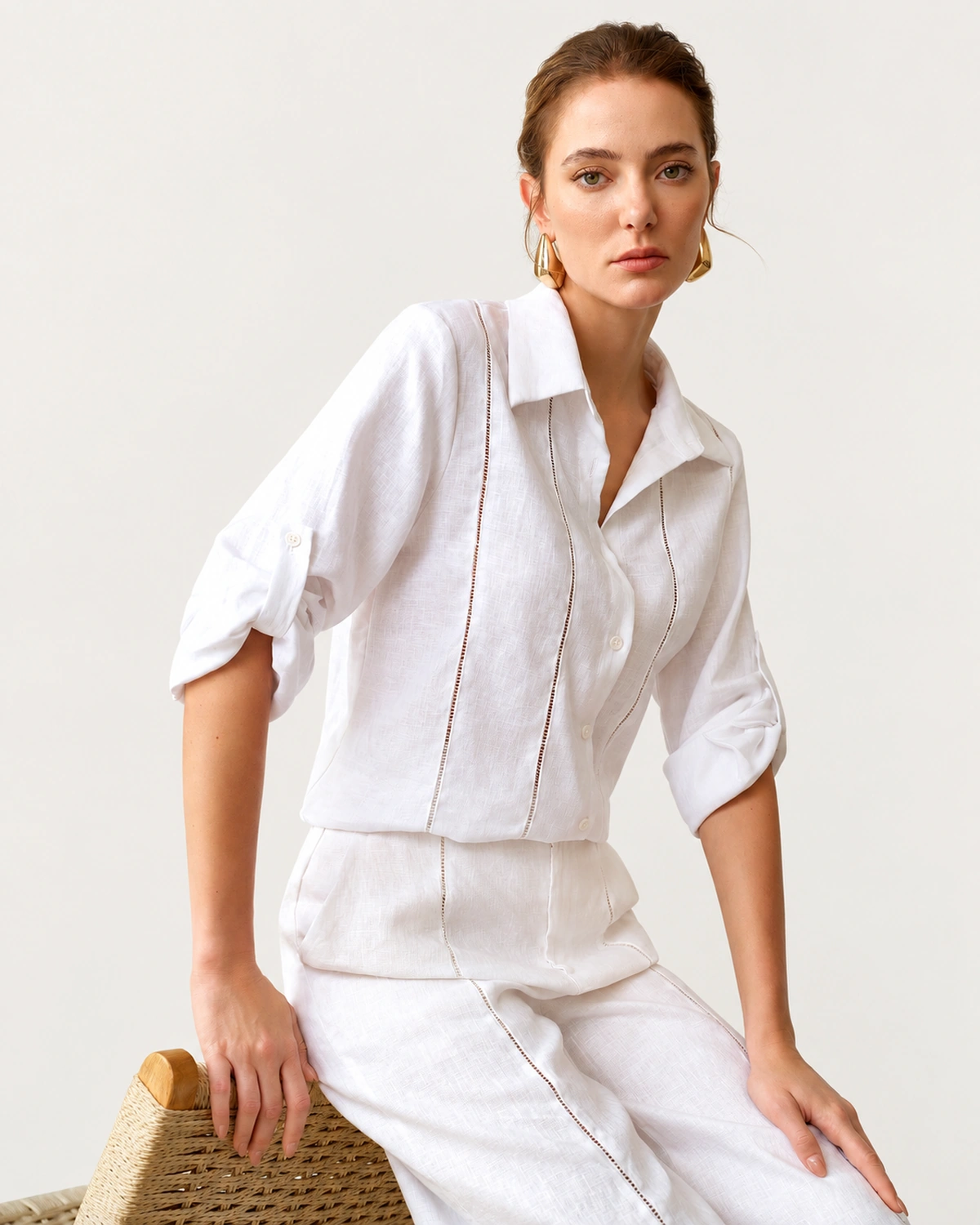 Modelo sentada em banco de palha vestindo camisa de puro linho off-white