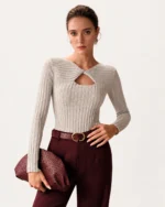 Modelo vestindo suéter em tricot canelado cinza-mescla com decote canoa e torção frontal vazada em estúdio mineral