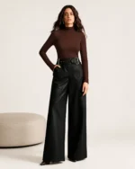 Look completo com calça pantalona feminina em couro preto e cinto largo
