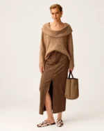 Modelo de corpo inteiro com suéter tricot canelado camel, saia de camurça marrom e bolsa tote em estúdio.