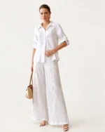 Modelo em corpo inteiro vestindo look completo com camisa de puro linho off-white e calça combinando
