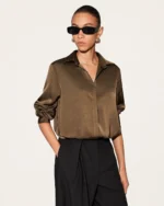 Enquadramento frontal em plano médio da camisa feminina de seda acetinada na cor café com fechamento embutido em estúdio mineral.