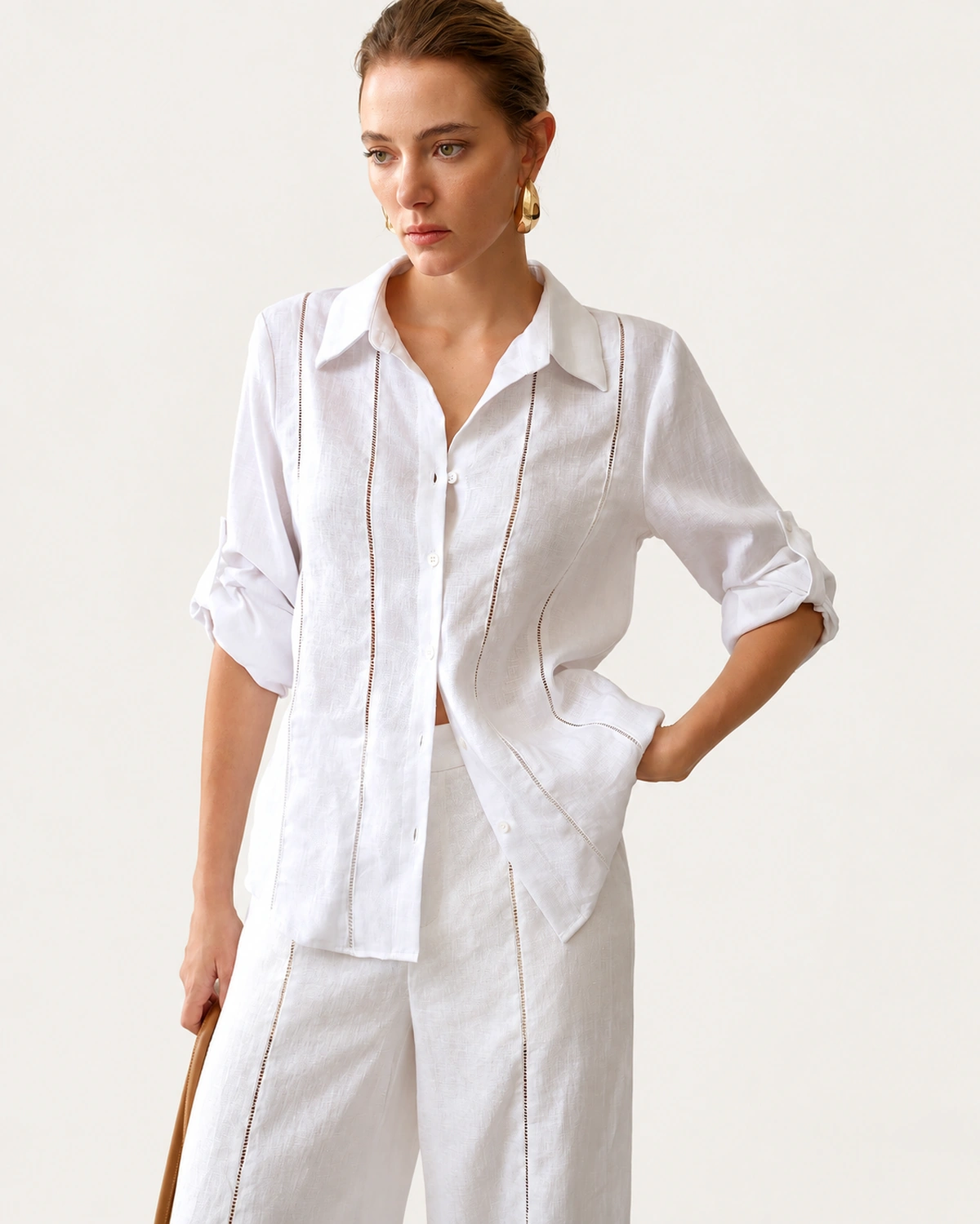Modelo vestindo camisa alfaiataria em puro linho off-white com decote sutil e manga dobrada