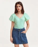 Modelo em plano médio frontal vestindo blusa texturizada com mangas bufantes e decote em V Verde-Menta.