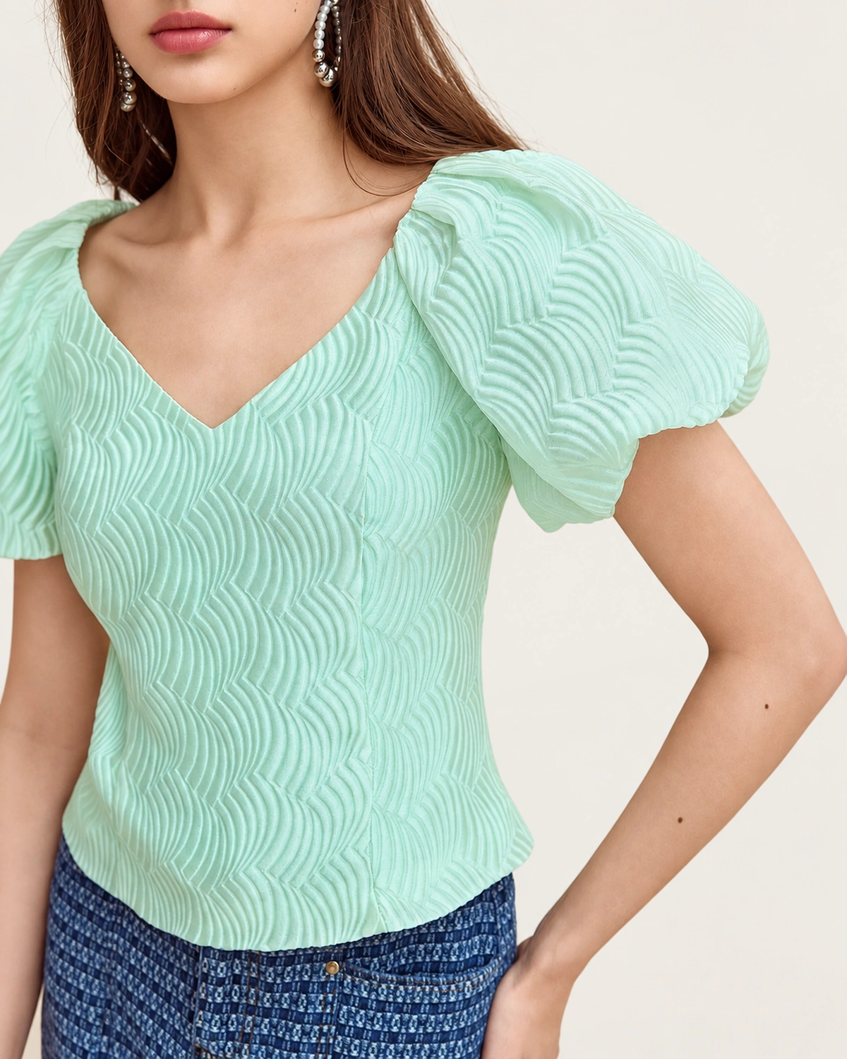 Detalhe do decote em V aberto e rica textura ondulada em relevo da blusa Verde-Menta.