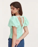 Vista posterior da blusa Verde-Menta com decote profundo em V traseiro e laço de fita delicado.