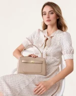 Plano médio da modelo usando a bolsa baú estruturada areia no ombro com alça longa transversal