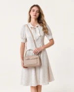 Editorial destacando o porte elegante da bolsa baú estruturada areia no antebraço em composição sofisticada