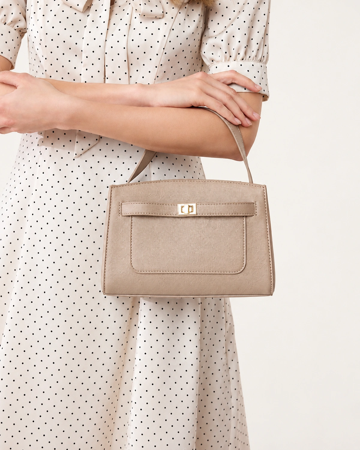 Modelo vestindo vestido de poá segurando a bolsa baú estruturada areia no antebraço