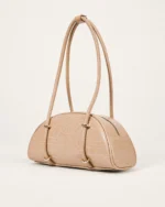 Bolsa meia-lua em PU textura croco areia apoiada no solo mineral em vista três quartos.
