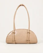 Bolsa meia-lua com textura croco e barretas metálicas na cor areia em vista frontal.