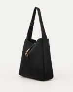 Perspectiva três quartos da bolsa shoulder bag preta destacando base e profundidade estruturada