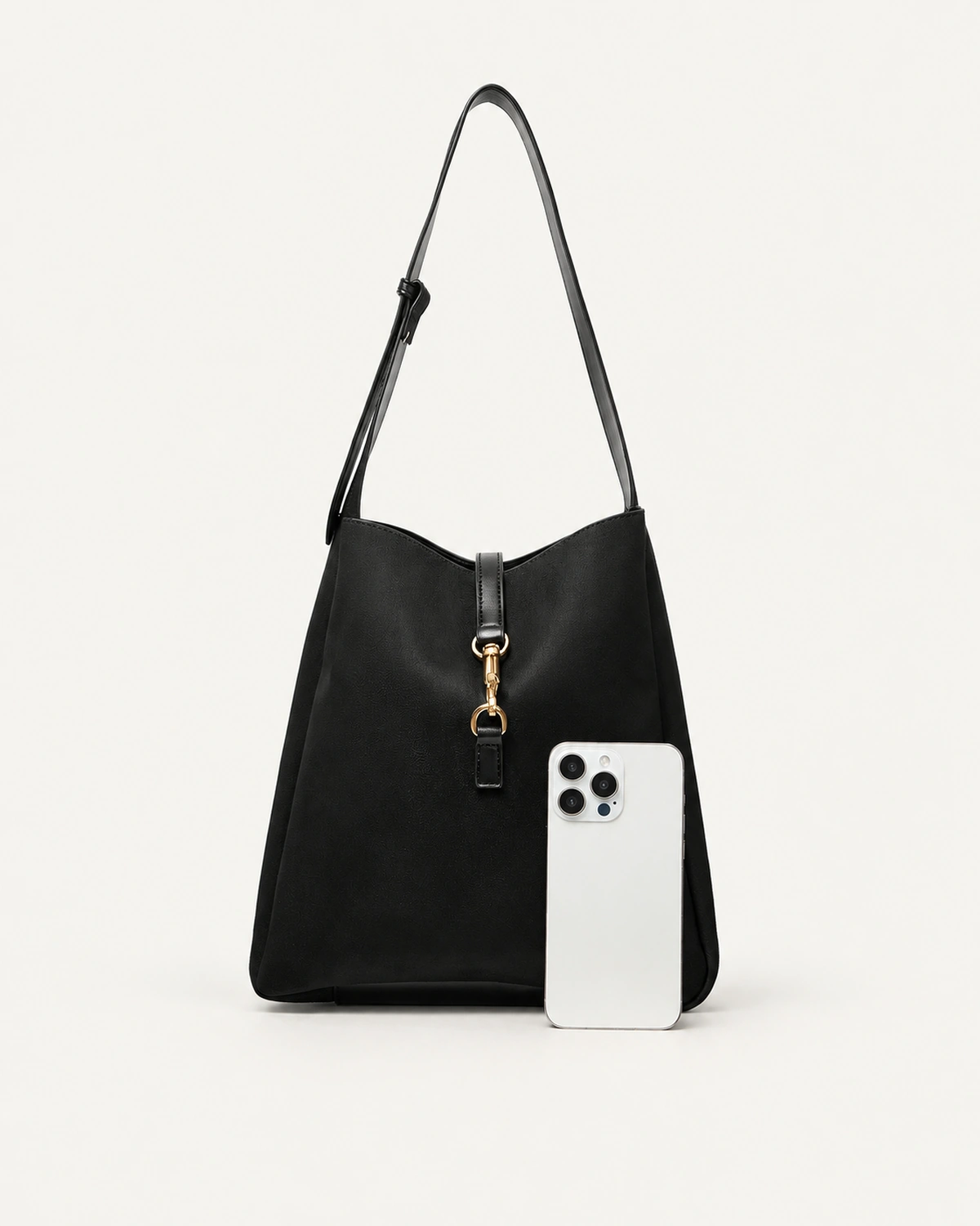 Bolsa shoulder bag preta com smartphone em escala no piso mineral comprovando capacidade para itens pessoais