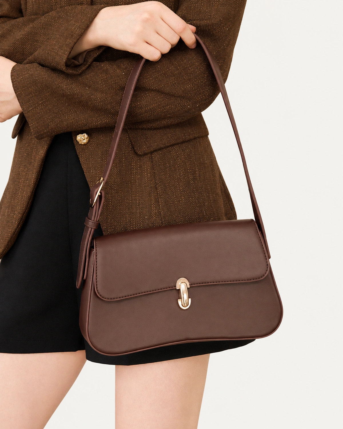 Bolsa tiracolo Café em couro liso, modelo em retrato editorial de ateliê.