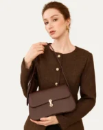 Modelo apresenta bolsa tiracolo Café em couro liso em pose editorial.