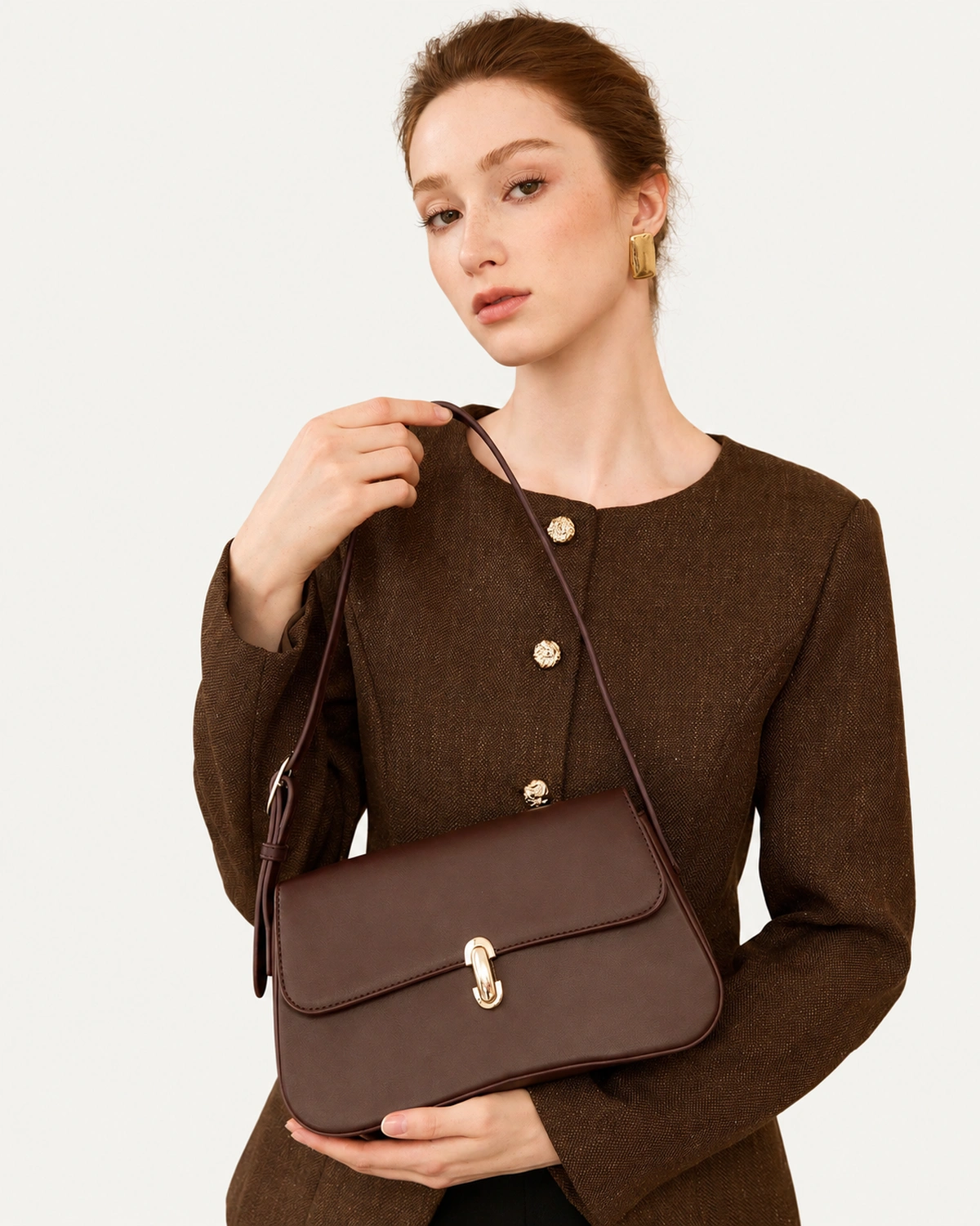 Modelo apresenta bolsa tiracolo Café em couro liso em pose editorial.