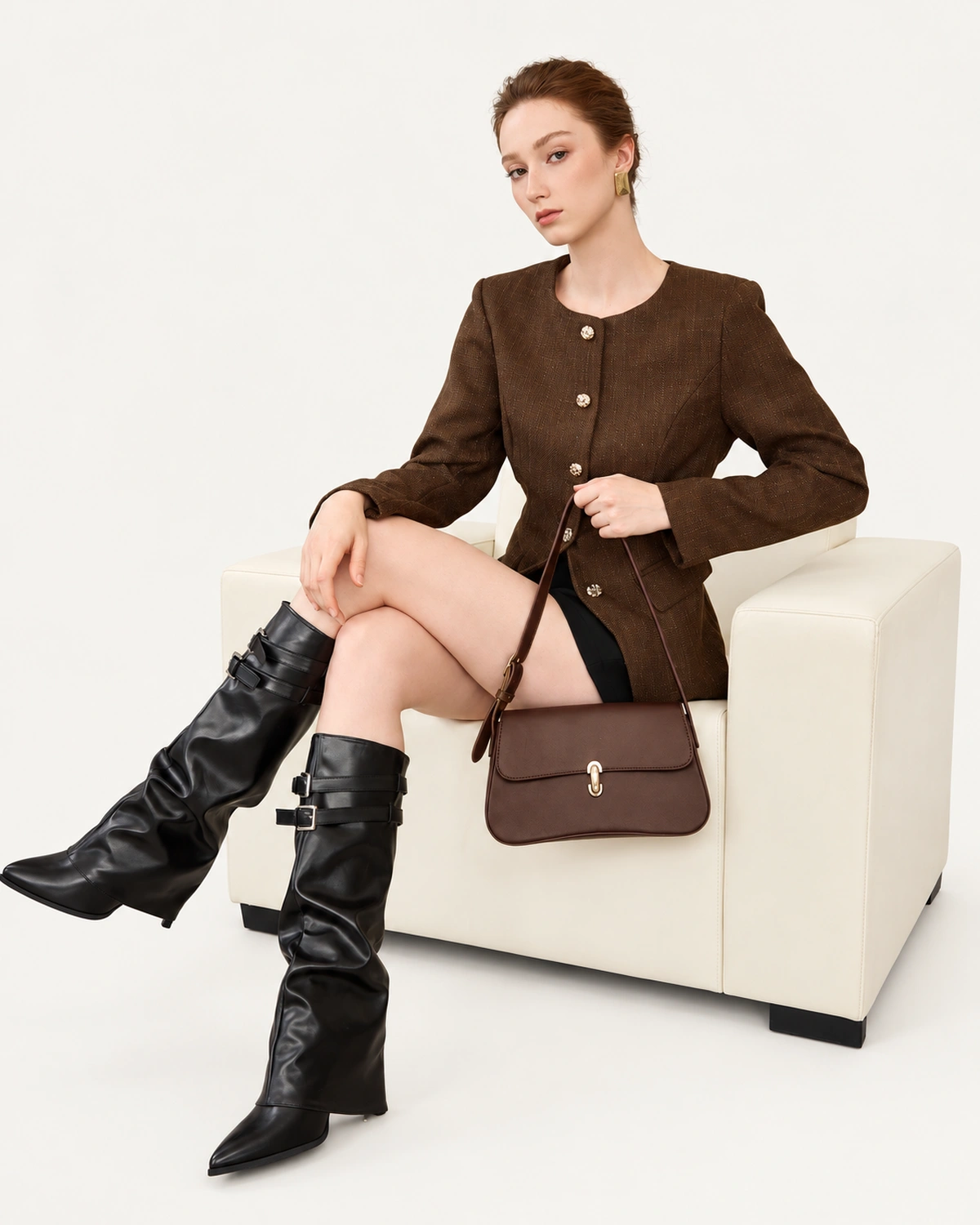 Modelo sentada em poltrona com bolsa tiracolo Café em couro liso.