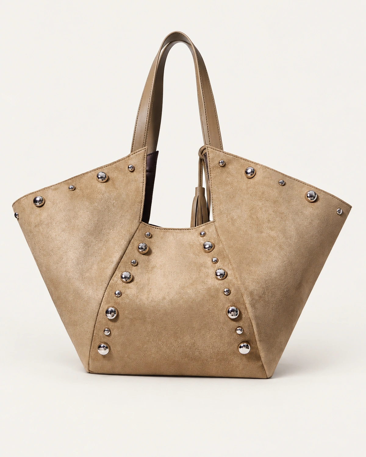 Bolsa tote em suede marrom conhaque em perspectiva destacando abas laterais expandidas no solo mineral