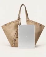 Bolsa tote em suede marrom conhaque ao lado de tablet no solo mineral demonstrando ampla capacidade interna
