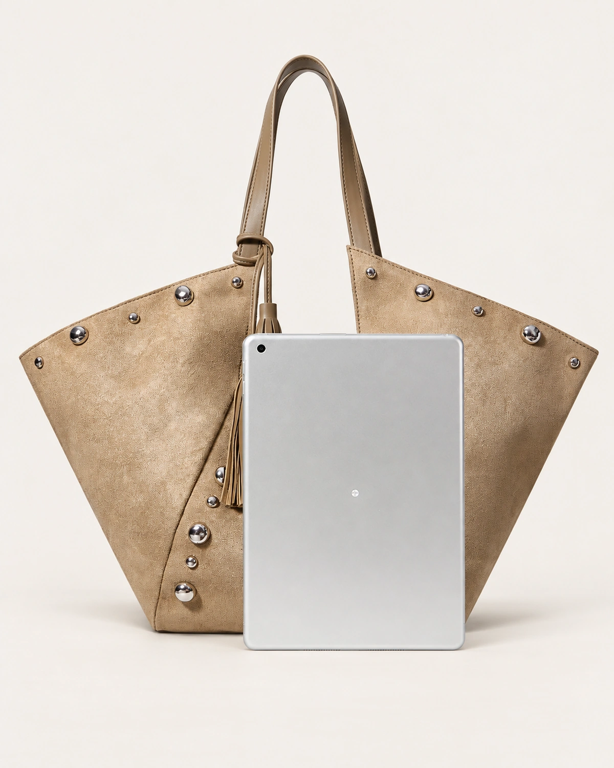Bolsa tote em suede marrom conhaque ao lado de tablet no solo mineral demonstrando ampla capacidade interna