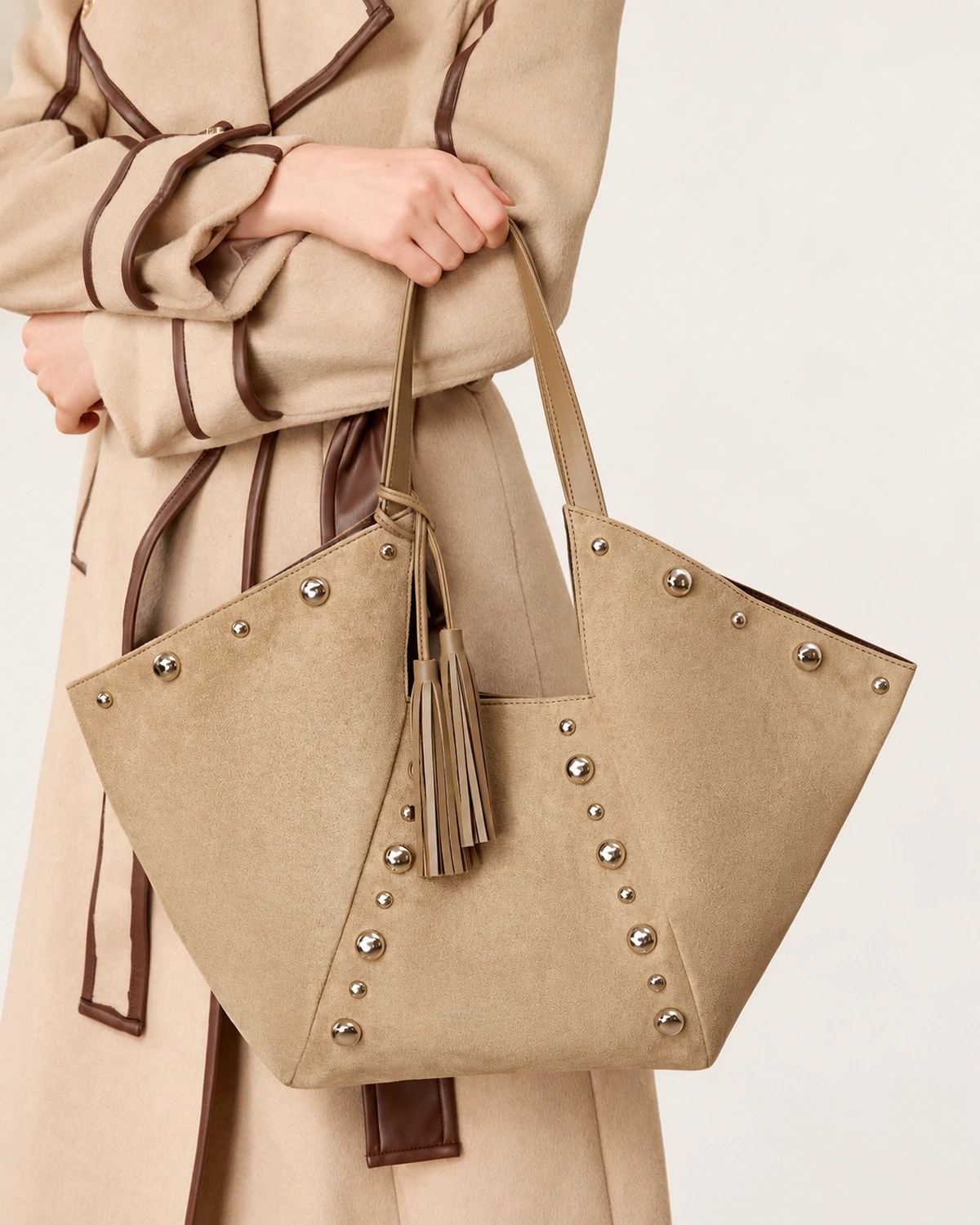 Plano médio da modelo segurando a bolsa tote em suede com sobretudo de lã em estúdio mineral