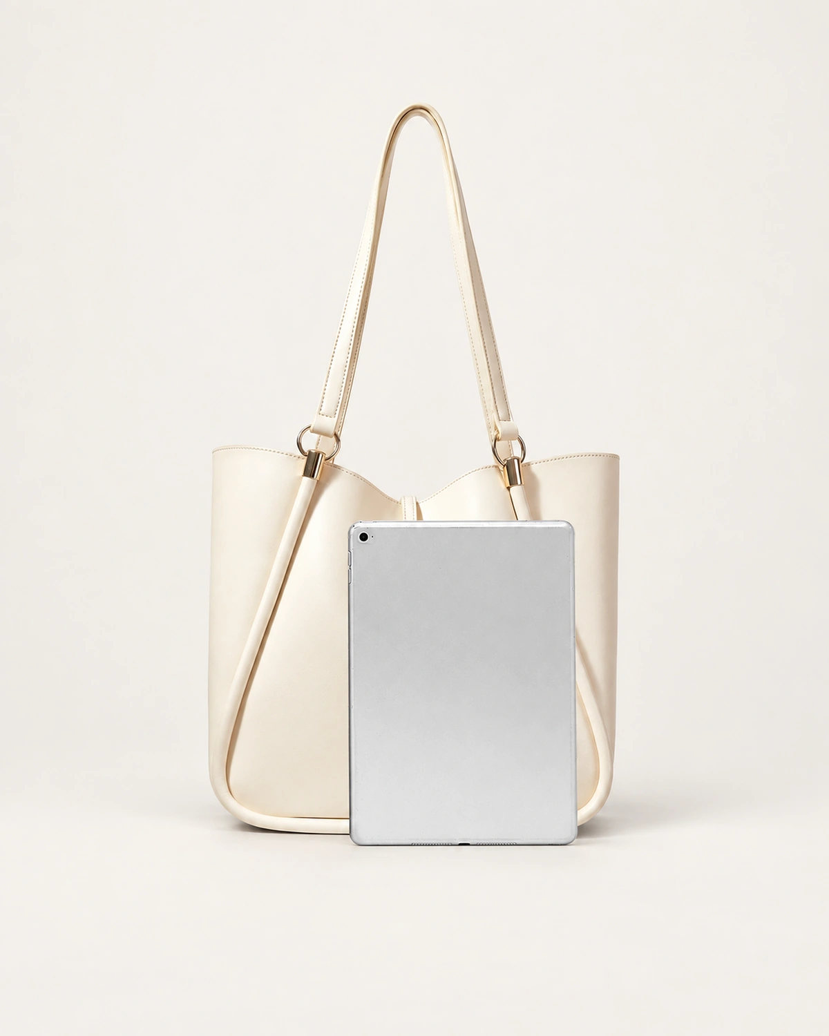 Bolsa tote executiva bege areia ao lado de tablet no solo mineral demonstrando ampla capacidade interna