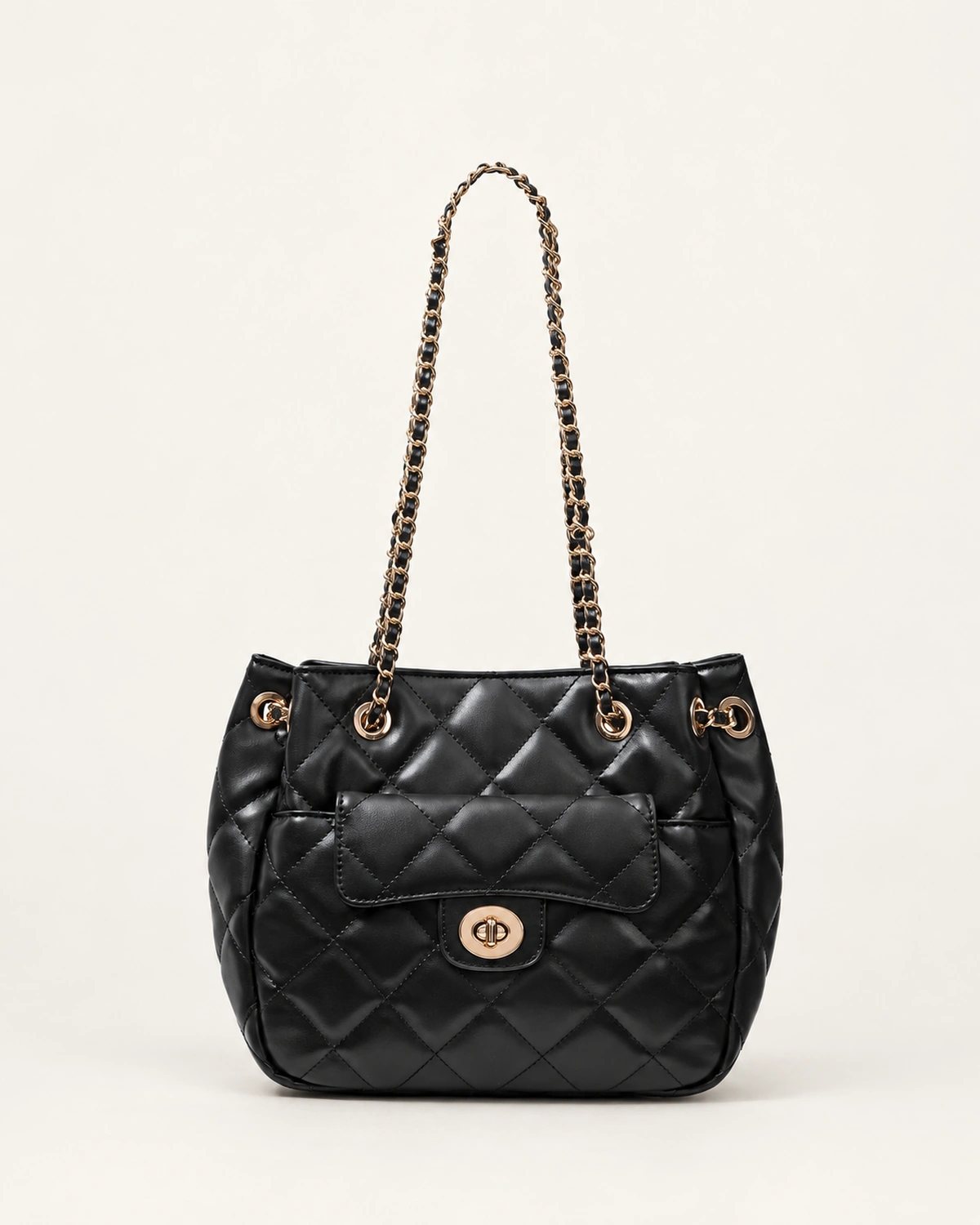 Bolsa tote acolchoada preta em matelassê com bolso frontal e alças de corrente dourada no solo mineral