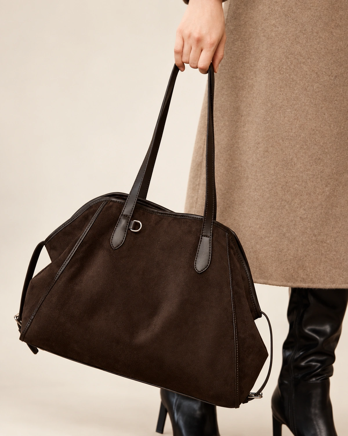 Plano detalhe da modelo carregando a bolsa tote marrom na mão no estúdio mineral