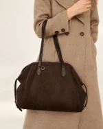 Modelo com sobretudo bege de lã carregando a bolsa tote marrom no ombro no estúdio mineral