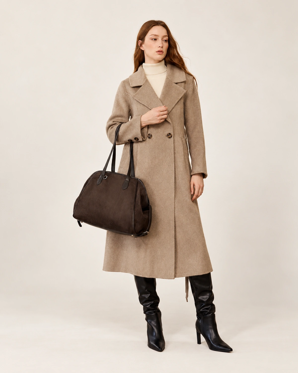 Modelo de corpo inteiro com casaco bege e botas pretas carregando a bolsa tote em suede marrom no estúdio mineral