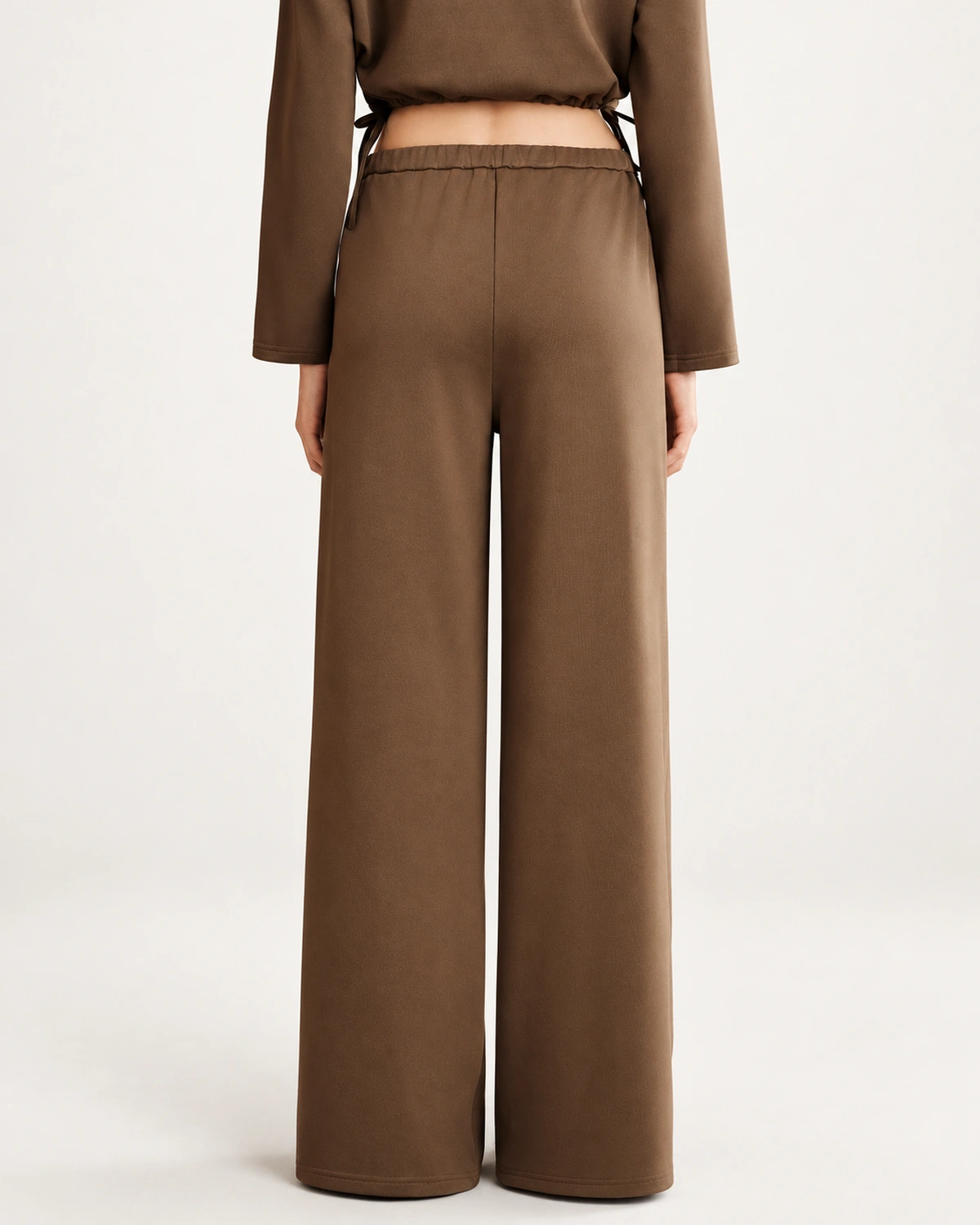 Vista posterior da modelo vestindo calça pantalona fluida em estúdio mineral