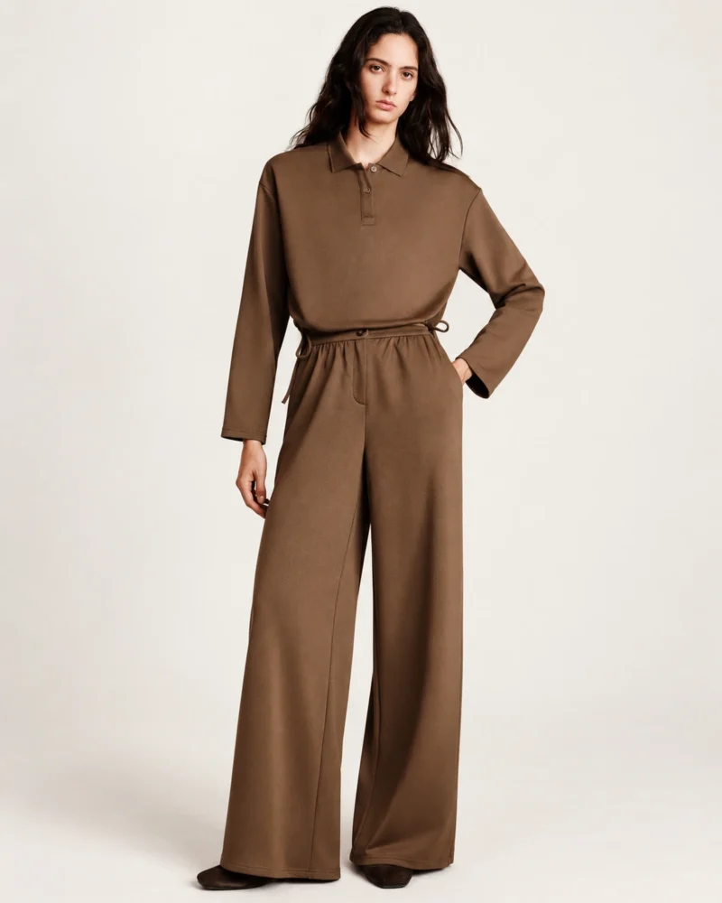 Plano frontal da modelo vestindo calça pantalona fluida marrom café em estúdio mineral