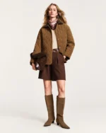 Plano inteiro da modelo vestindo look completo com casaco acolchoado e botas em estúdio mineral