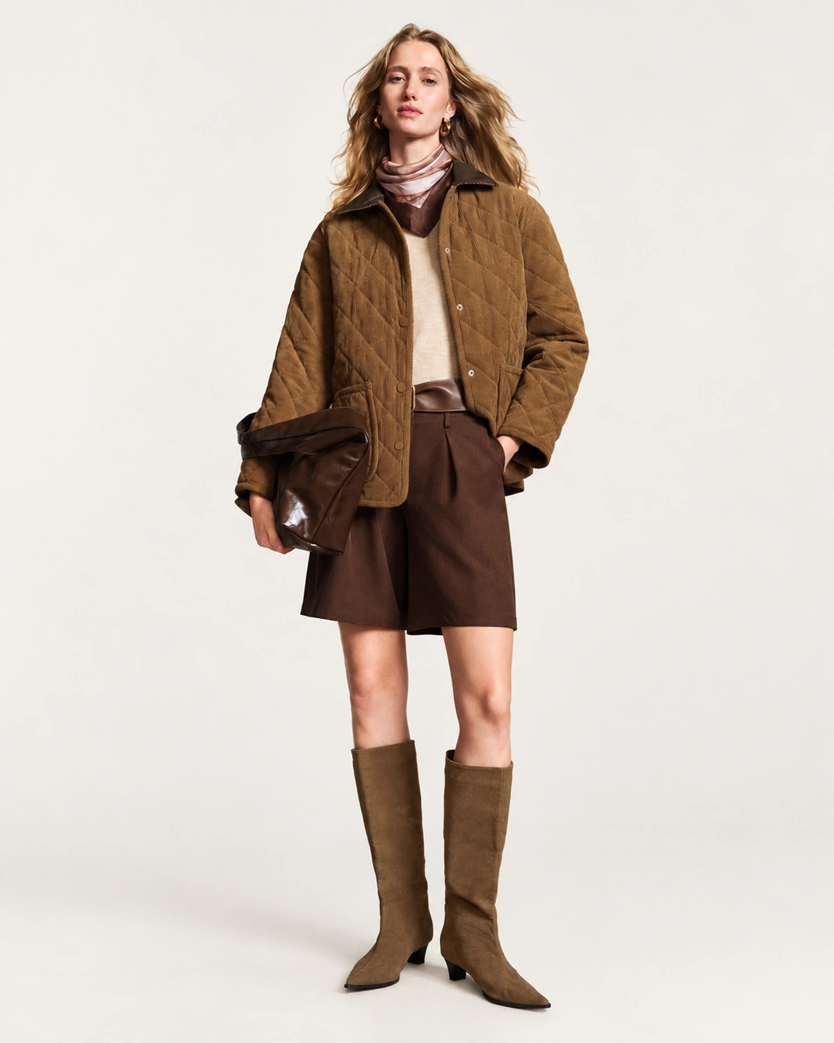 Plano inteiro da modelo vestindo look completo com casaco acolchoado e botas em estúdio mineral