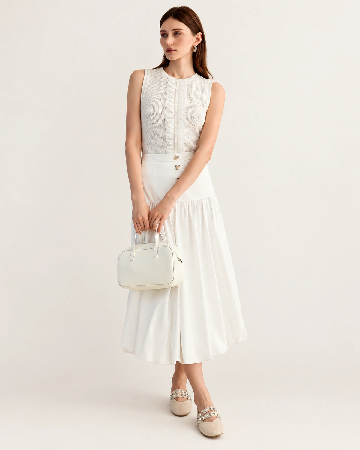 Modelo em semiperfil de corpo inteiro vestindo saia midi de alfaiataria plissada off-white.