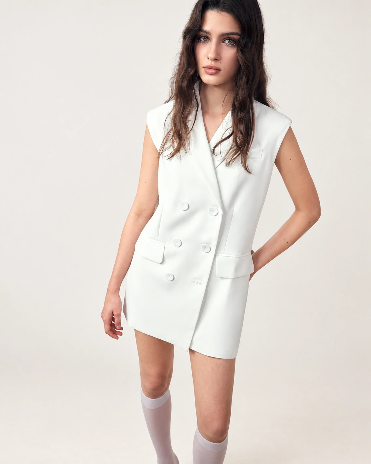 Plano médio frontal da modelo vestindo vestido blazer alfaiataria com abotoamento duplo off-white.