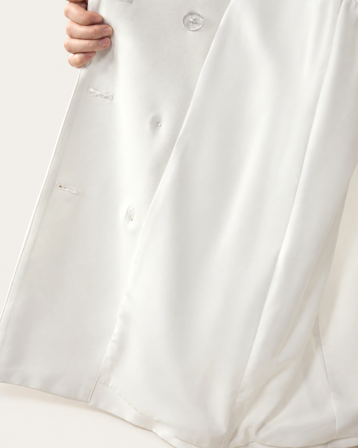 Detalhe da costura interna, forro acetinado e contra-botão de sustentação do vestido blazer off-white.