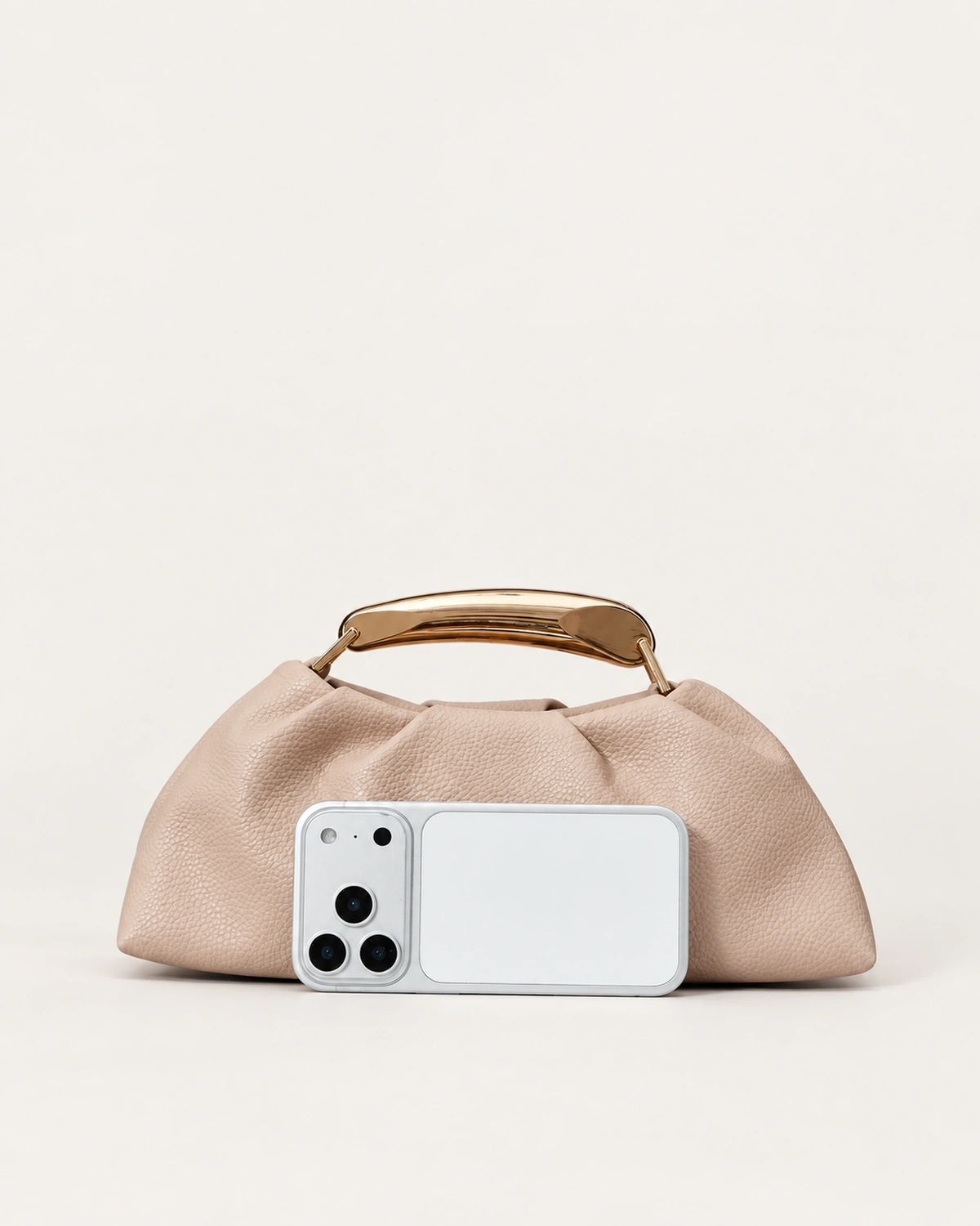 Bolsa Satchel Drapeada com Alça Escultural Metálica em tom areia com alça escultural metálica.