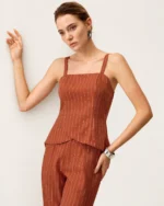 Editorial de moda com modelo em plano médio vestindo top de alfaiataria risca de giz terracota.