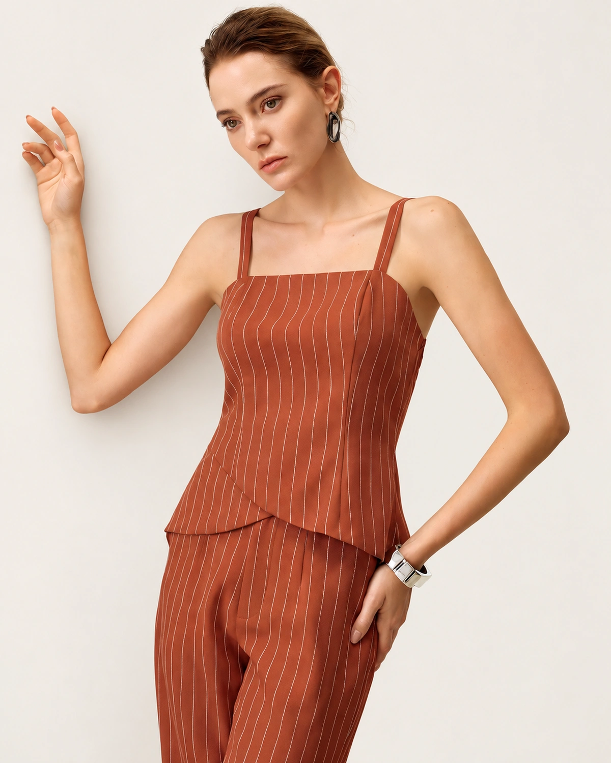 Editorial de moda com modelo em plano médio vestindo top de alfaiataria risca de giz terracota.
