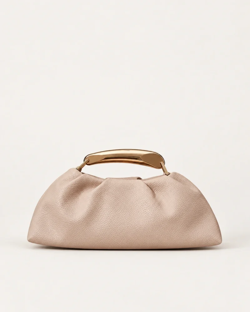 Bolsa Satchel Drapeada com Alça Escultural Metálica em tom areia com alça escultural metálica.