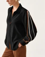 Plano médio aproximado da camisa feminina preta clássica com vivos contrastantes solta sobre calça marrom
