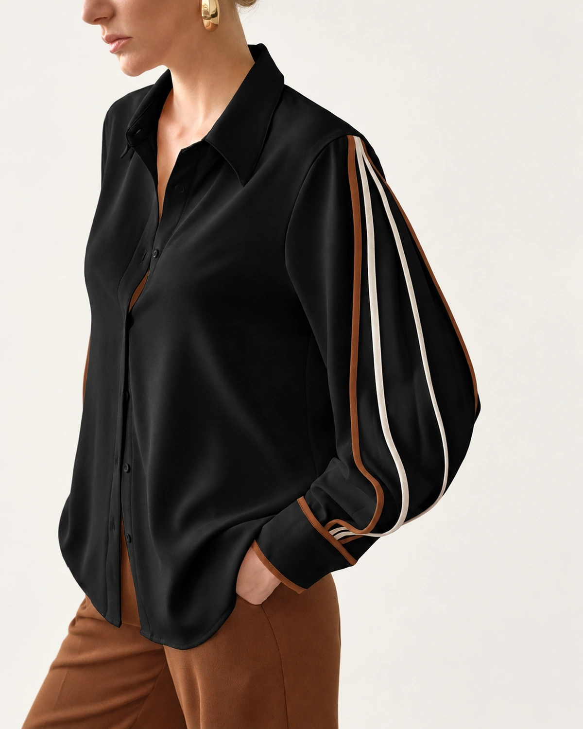 Plano médio aproximado da camisa feminina preta clássica com vivos contrastantes solta sobre calça marrom