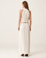 Vista de costas da modelo vestindo colete halter e saia midi em linho off-white.